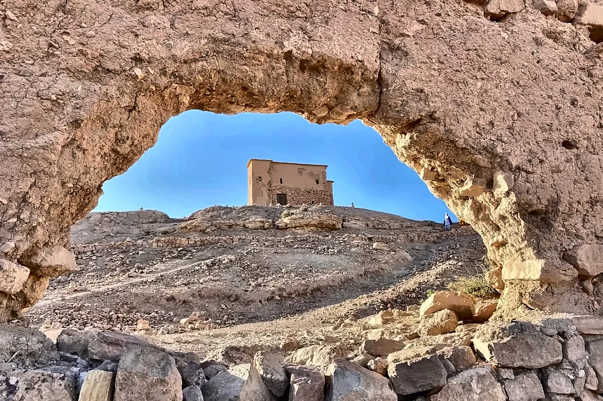 Una kasbah inquadrata da un arco di pietra in rovina