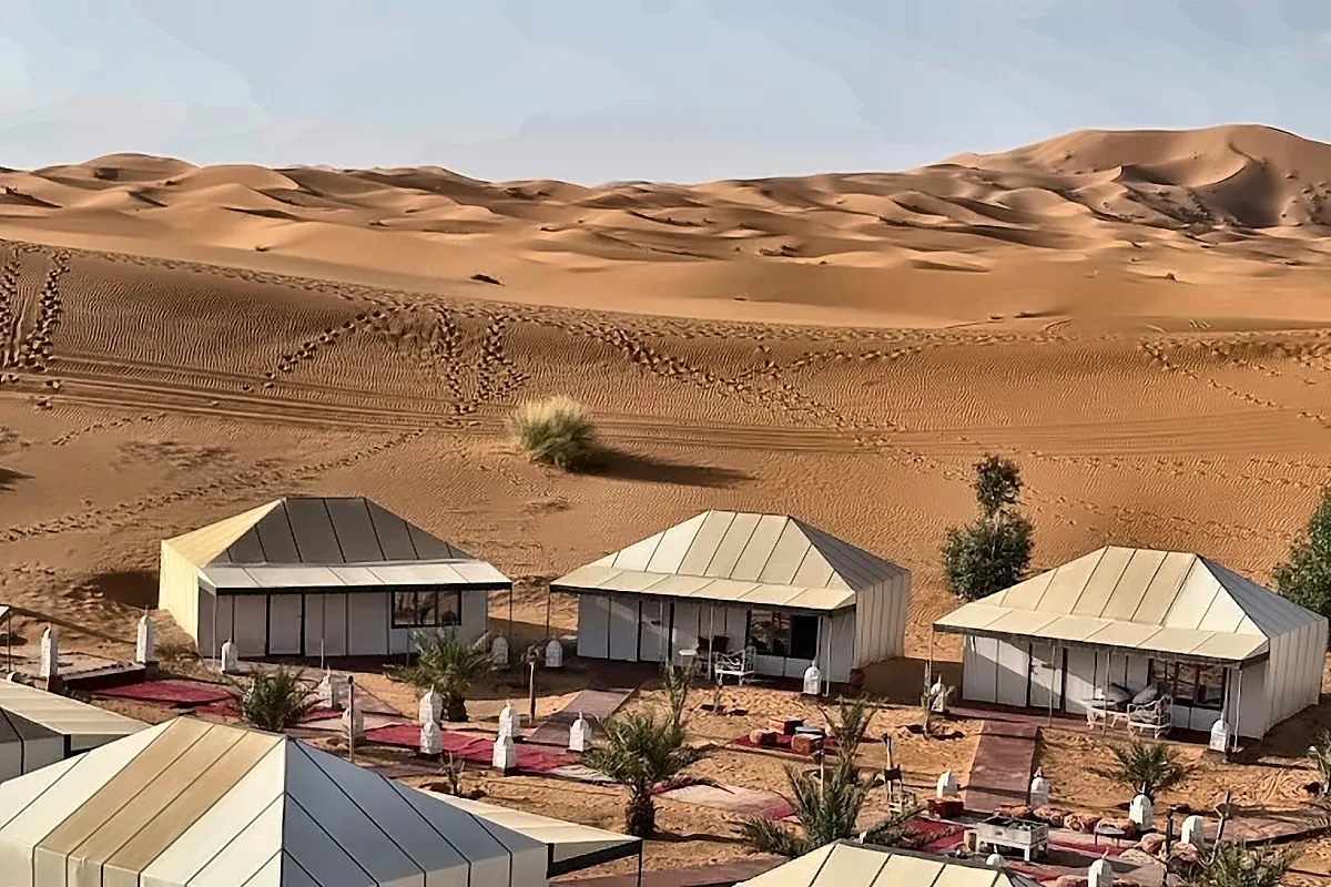 Le tende bianche di un campo allineate ai piedi delle dune