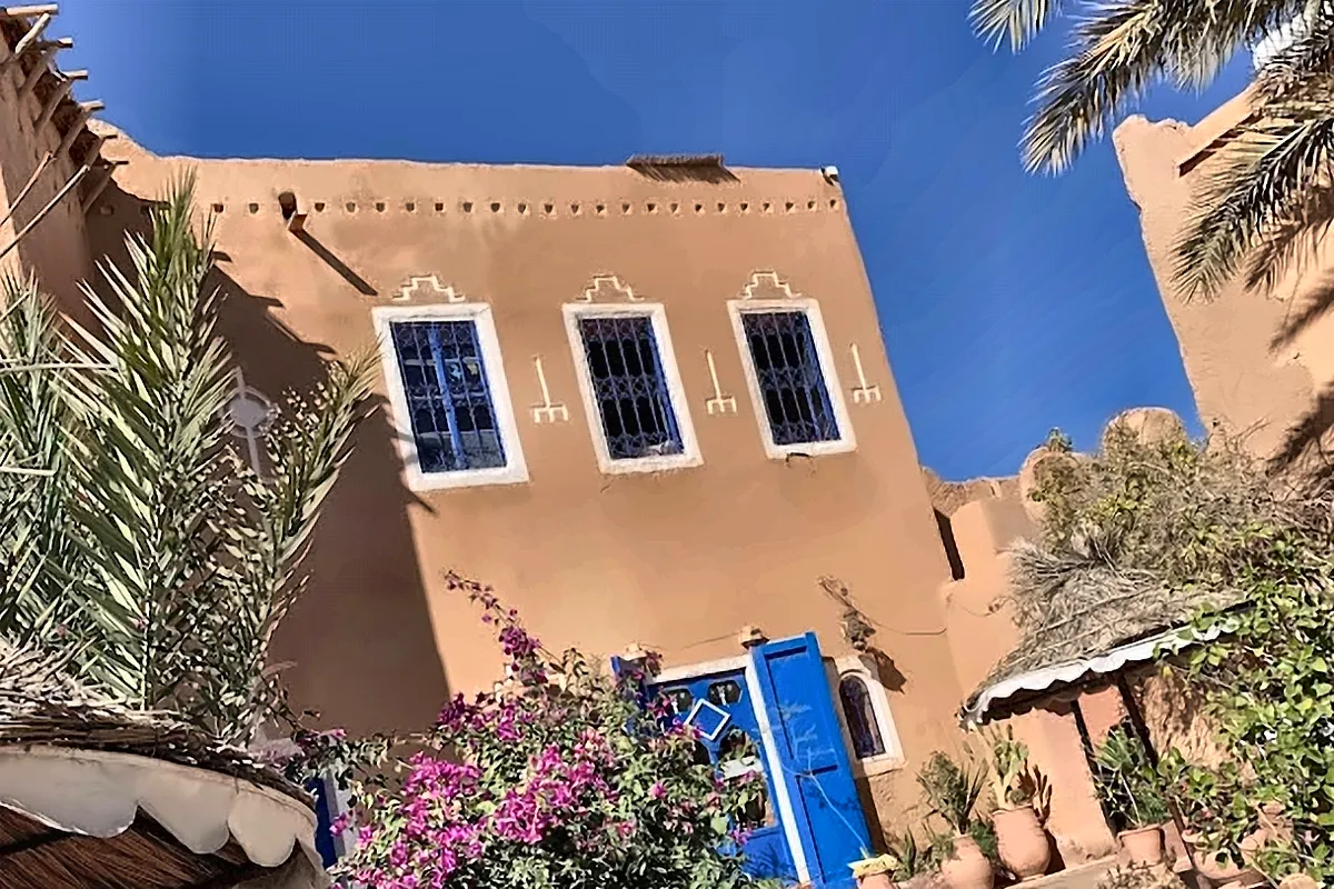 Casa bianca e azzurra con i fiori davanti alla porta