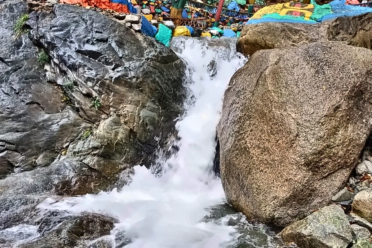 Cascata fra le rocce, con le bandierine colorate tese sopra