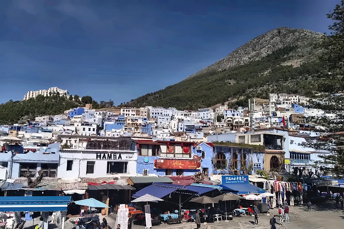 La piazza del mercato di Chefchaouen con la citta azzurra e la montagna alle spalle
