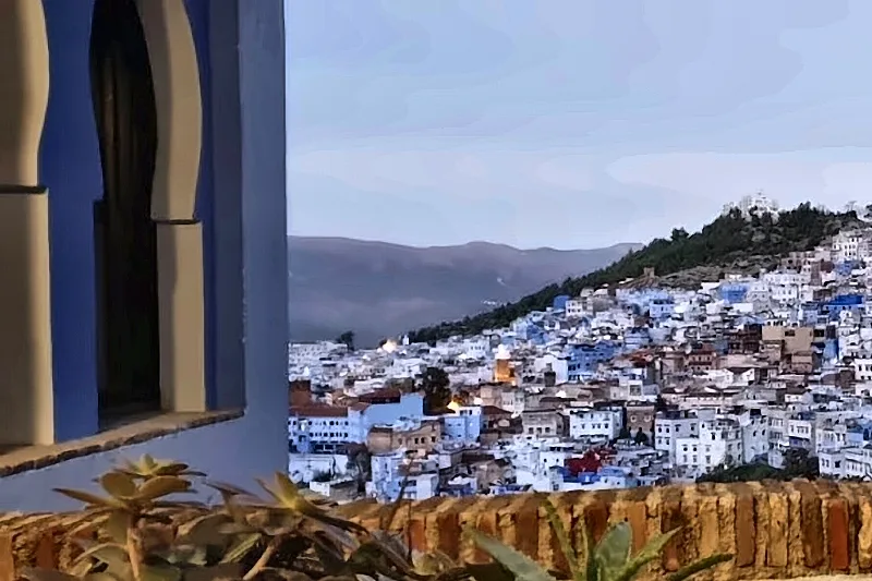 La città blu al crepuscolo vista da una terrazza, fra l'arco e le piante
