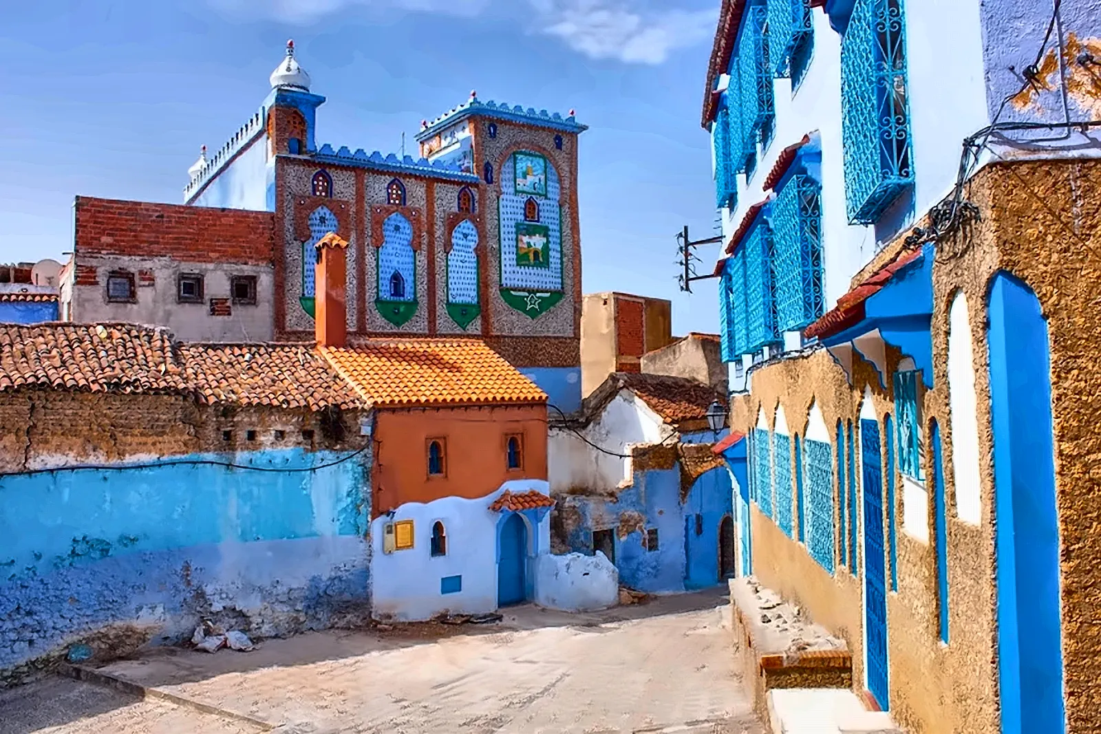 Vicolo azzurro di Chefchaouen con la moschea e la casa arancione
