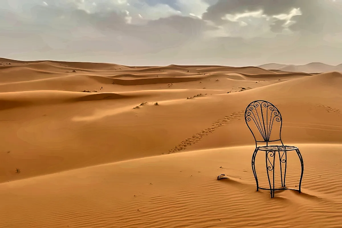 Una sedia di ferro battuto lasciata sulla sabbia fra le dune