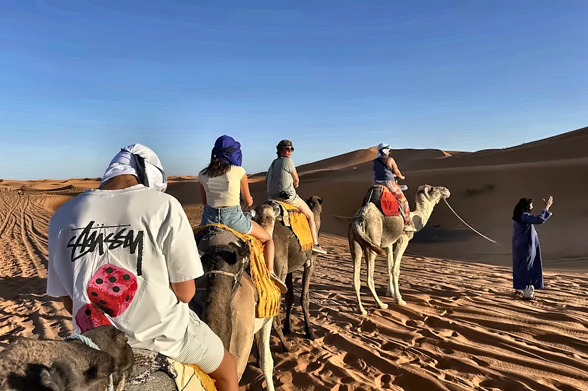 Un gruppo di viaggiatori con i cammellieri sulle dune