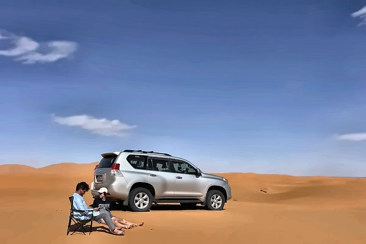 Un fuoristrada bianco fermo sulla sabbia, con il deserto intorno