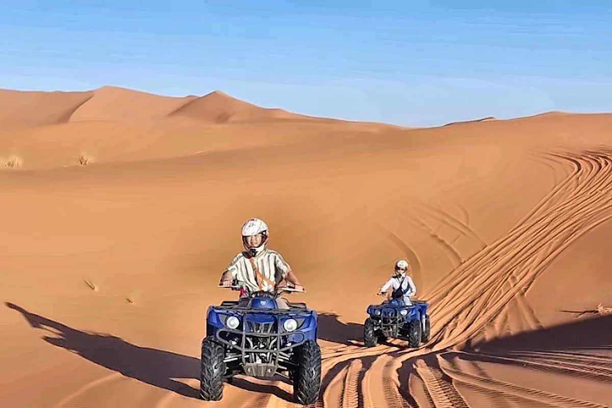 Un quad che risale una duna lasciando la traccia sulla sabbia