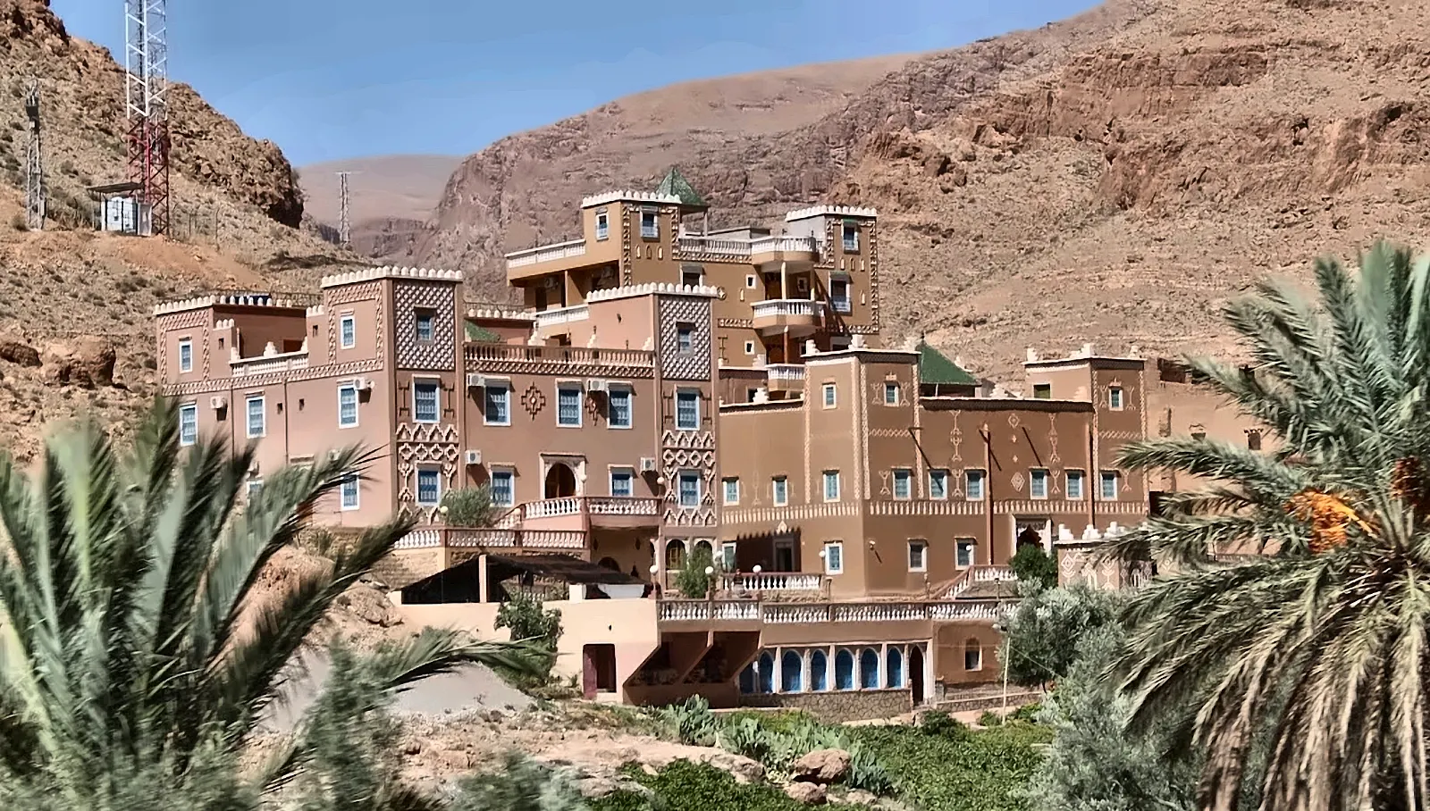 Grande edificio in stile kasbah fra le palme, ai piedi delle pareti
